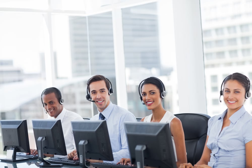Line of call centre employees smiling and working on computers